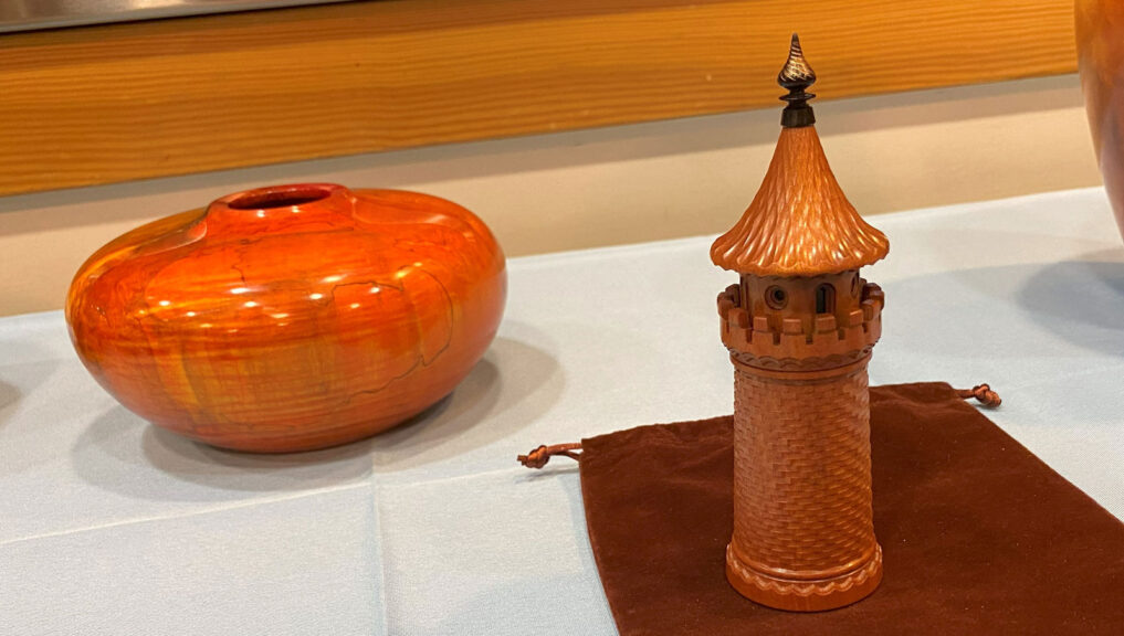 Jon Sauer: castle-shaped box turned with ornamental lathe. The orange hollow-form in the background is turned by Mark Koenig.