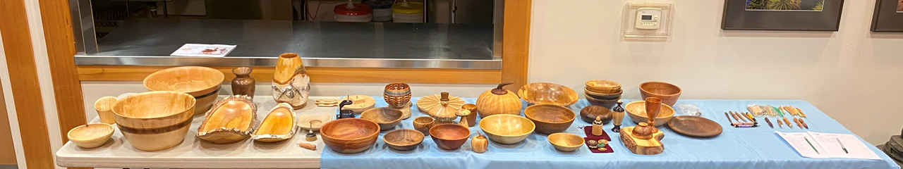 A table full of turned bowls, pens, and other woodturning projects for Woodturners Newsletter.