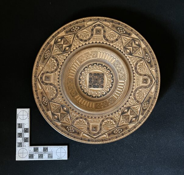 A turned plate embellished with very intricate chip carving