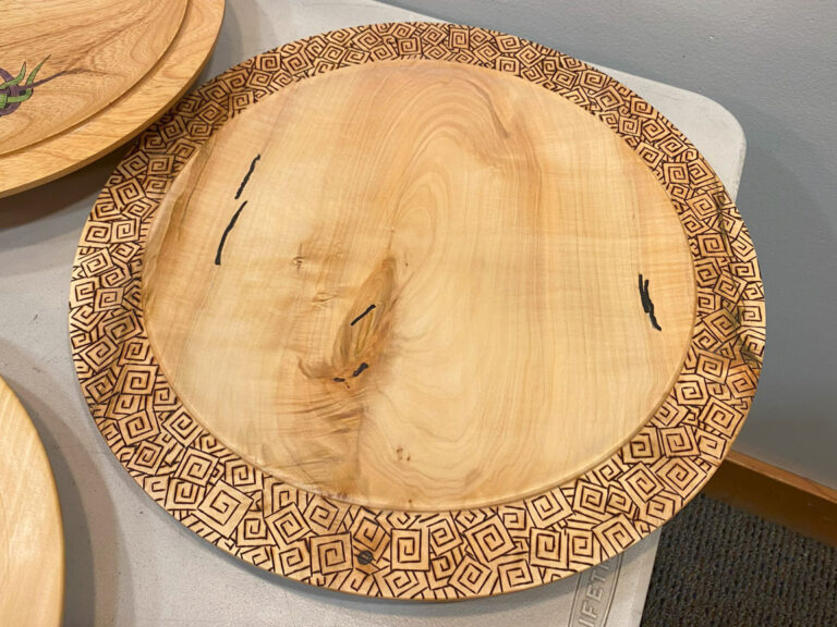 A wooden platter with embellished rim.